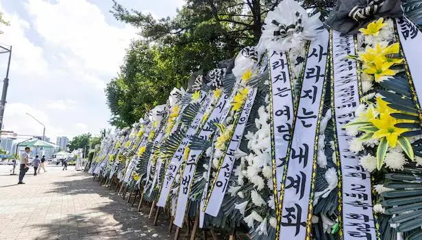 韩国国会大厦门口摆了几十个花圈